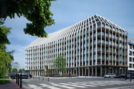 Moderní budova Victoria Palace s výraznou fasádou tvořenou svislými bílými lamelami a prosklenými balkony, obklopená zelení.